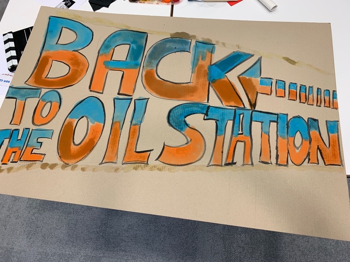 Affiche colorée avec le texte 'BACK TO THE OIL STATION' en lettres stylisées orange et bleues.