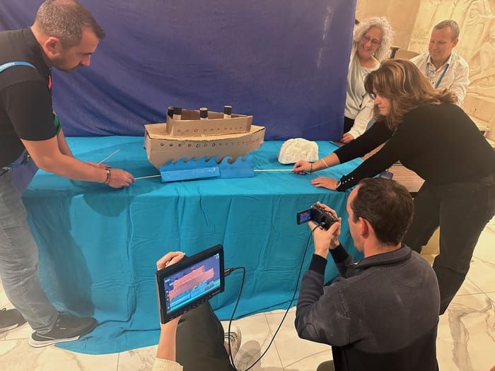 Maquette de bateau en carton animée devant un fond bleu, effet spécial fabriqué par l'équipe en tournage