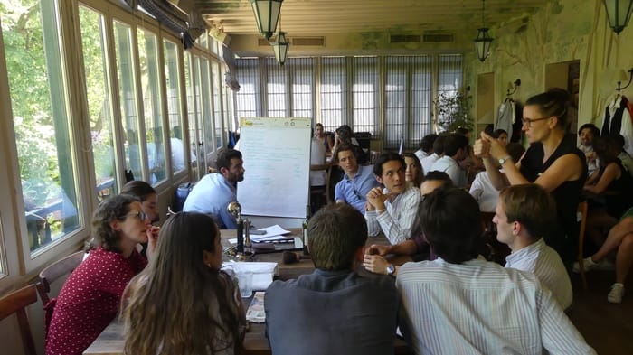 Atelier collectif, échanges autour d’un paperboard dans une salle lumineuse Équipe en team building écrivant le scénario de son court-métrage autour d'un paperboard
