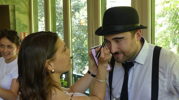 Retouche maquillage d’un comédien en costume de scène Collaboratrice maquillant un collègue costumé avant le tournage du court-métrage d'entreprise
