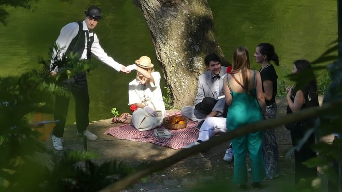 Pique-nique champêtre pendant un tournage, équipe réunie sous l’arbre Collaborateurs jouant une scène de pique-nique pendant le tournage de leur court-métrage