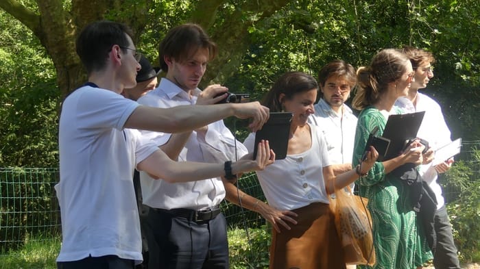 Équipe de tournage en extérieur, lecture d’un scénario Collaborateurs réglant le cadrage de la caméra lors d'un atelier court-métrage en extérieur